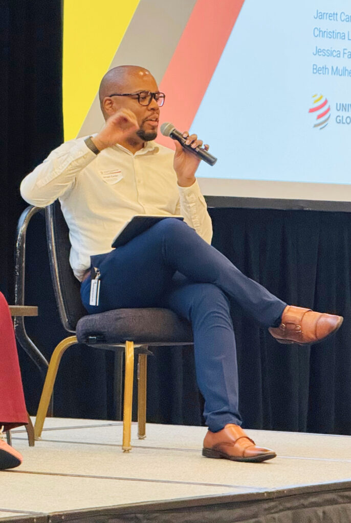 Jarrett Carter seated on a stage during a panel discussion.